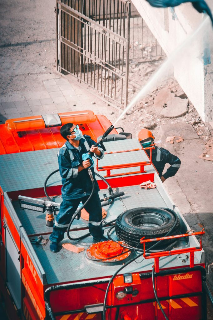 man in black jacket and blue denim jeans standing on red metal ladder